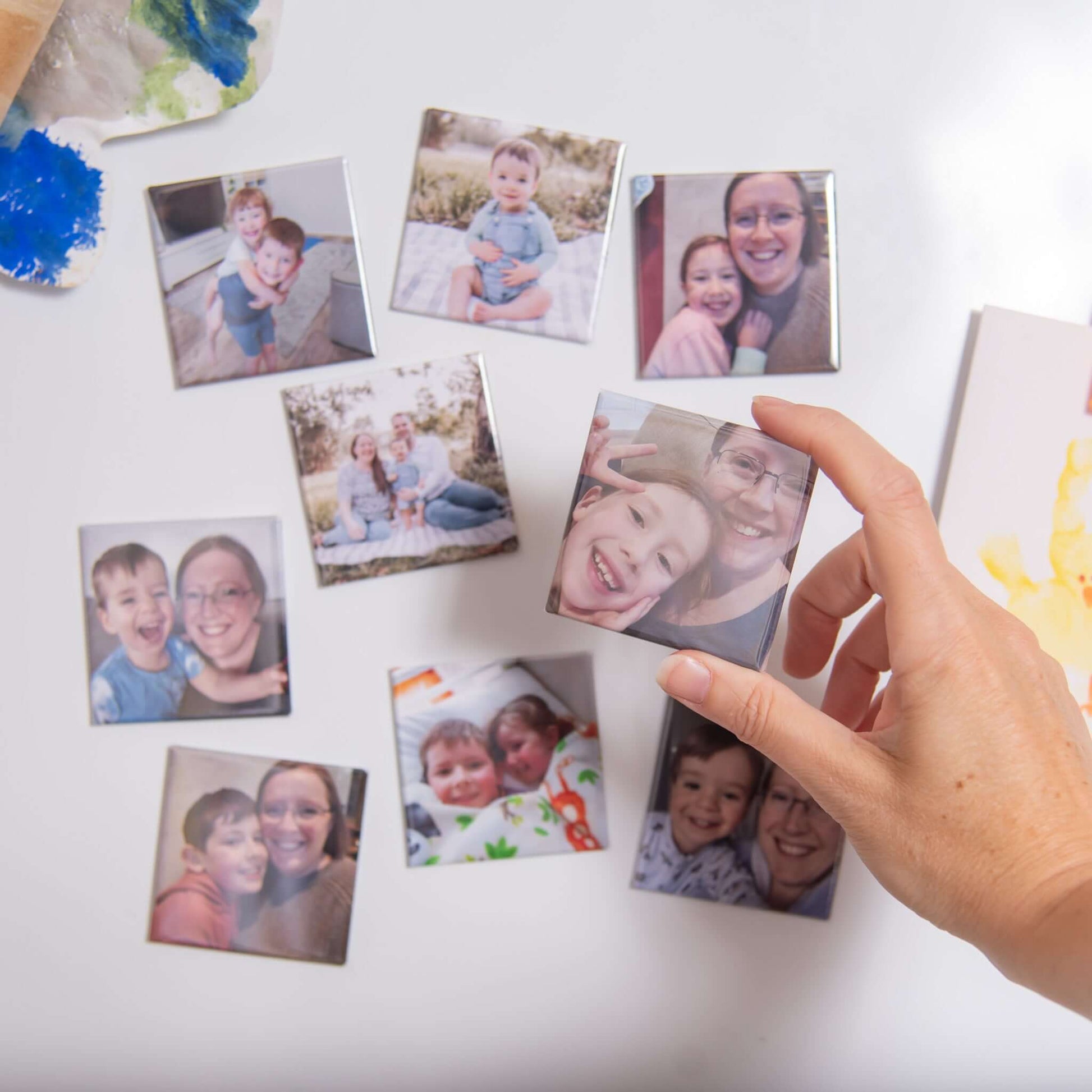 Custom photo magnets: family magnets on fridge with hand holding one magnet